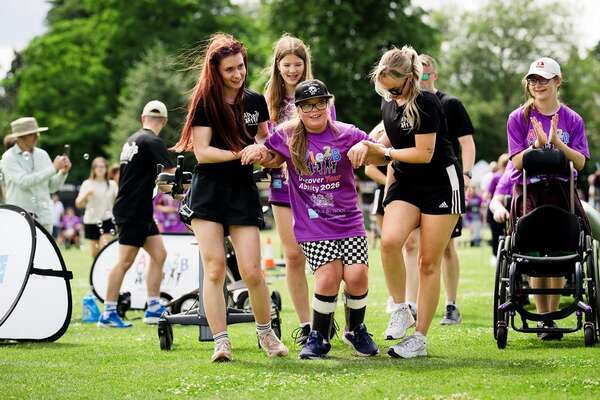Young person supported to cross finishing line